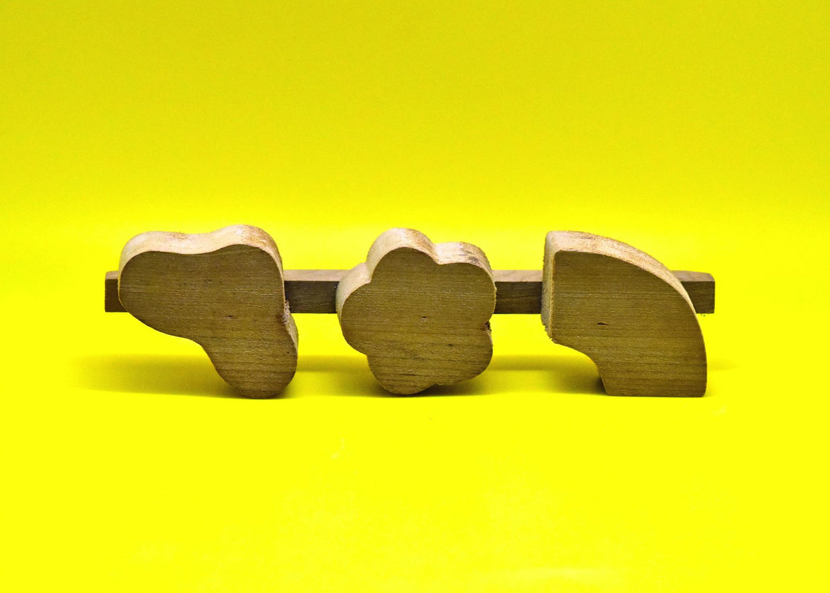 Trois éléphants en bois sur fond jaune